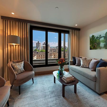 Tower Suites By Blue Orchid London Exterior photo The photo depicts a modern living room with a contemporary design. It features two stylish, circular chairs and a comfortable sofa adorned with various decorative pillows. A small coffee table is positioned in front of the sofa, topped with books and