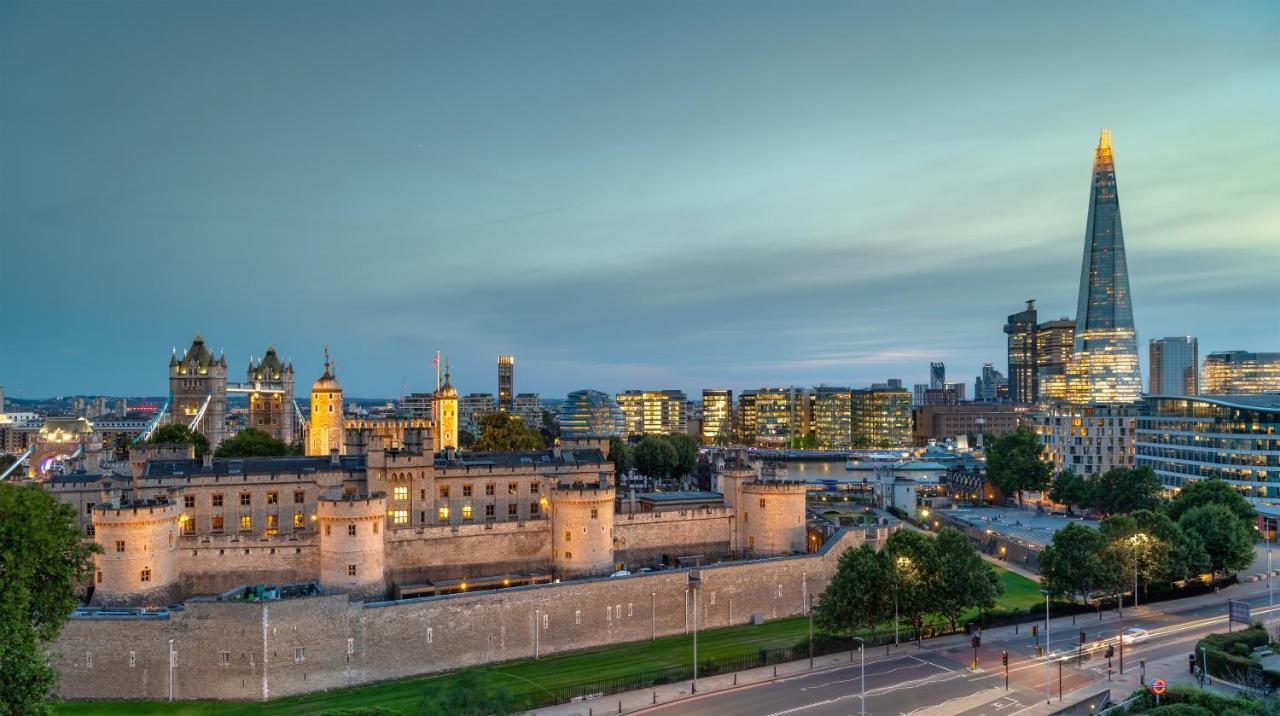 Tower Suites By Blue Orchid London Exterior photo The photo shows a view of a historical site and modern skyline. In the foreground, there is a prominent historical building, likely a castle or fortress, featuring tall towers and a stone wall. This structure is set against a backdrop of contemporary