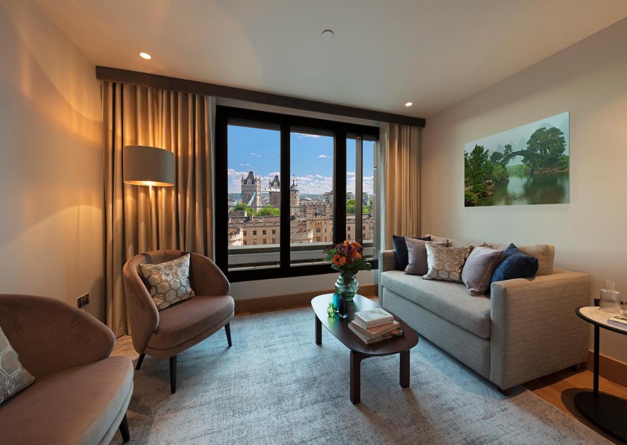 Tower Suites By Blue Orchid London Exterior photo The photo depicts a modern living room with a contemporary design. It features two stylish, circular chairs and a comfortable sofa adorned with various decorative pillows. A small coffee table is positioned in front of the sofa, topped with books and