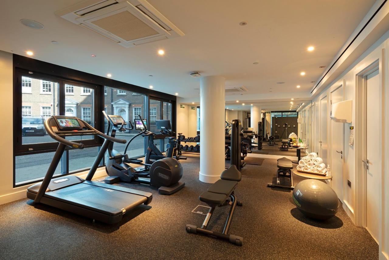 Tower Suites By Blue Orchid London Exterior photo The photo shows a modern gym interior featuring various exercise equipment. On one side, there are several cardio machines, including treadmills and an elliptical. The gym has a spacious, bright feel with large windows allowing natural light to enter