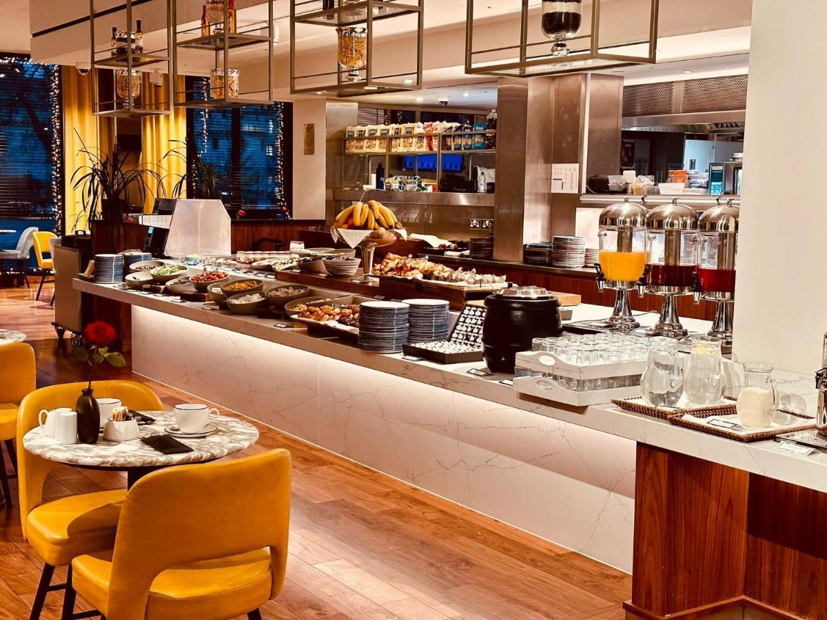 Tower Suites By Blue Orchid London Exterior photo The photo depicts a modern buffet setting, featuring an array of food items displayed elegantly on a long countertop. There are various dishes, likely including pastries, fruits, and other breakfast items, arranged neatly. In the background, there ar
