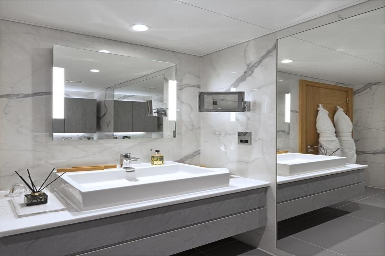 Tower Suites By Blue Orchid London Exterior photo The photo shows a modern bathroom featuring a sleek design. 

- **Vanity Area**: There is a rectangular sink set into a white countertop, paired with a minimalist faucet. 
- **Mirrors**: Above the sink, there is a large mirror that reflects the entir